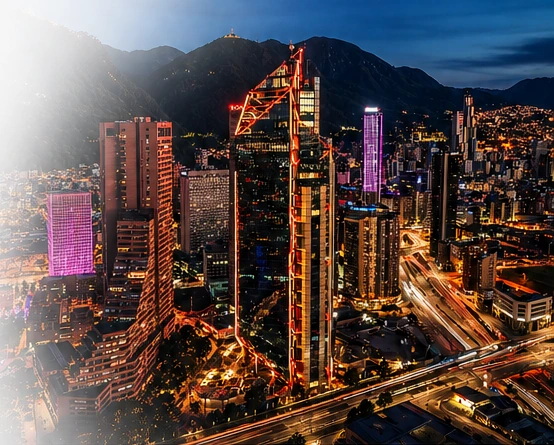 Centro financiero de Bogotá al anochecer, con montañas y vías iluminadas